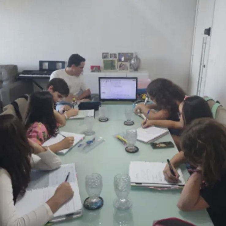 Aula de educação financeira na sala de casa com crianças ao redor da mesa